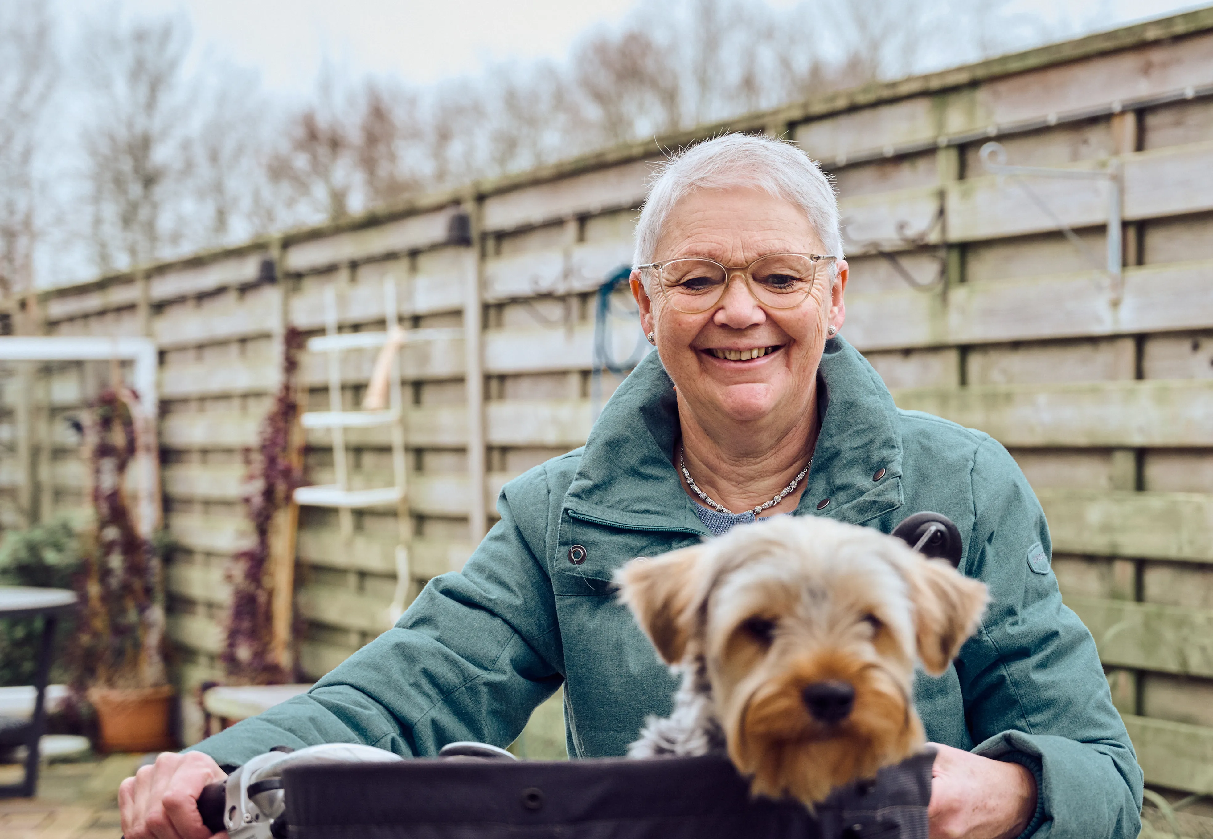 Smiling elderly woman with a small dog in a basket.